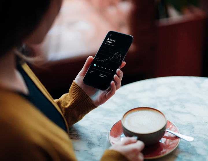 Person mit Handy und Kaffee in der Hand