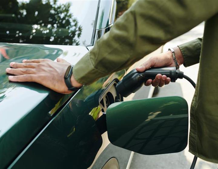 Green, electric vehicle being plugged into a charging station