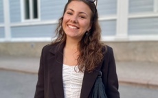 A picture of Thelma outdoors. She has dark wavy hairs and is wearing sunglasses here.