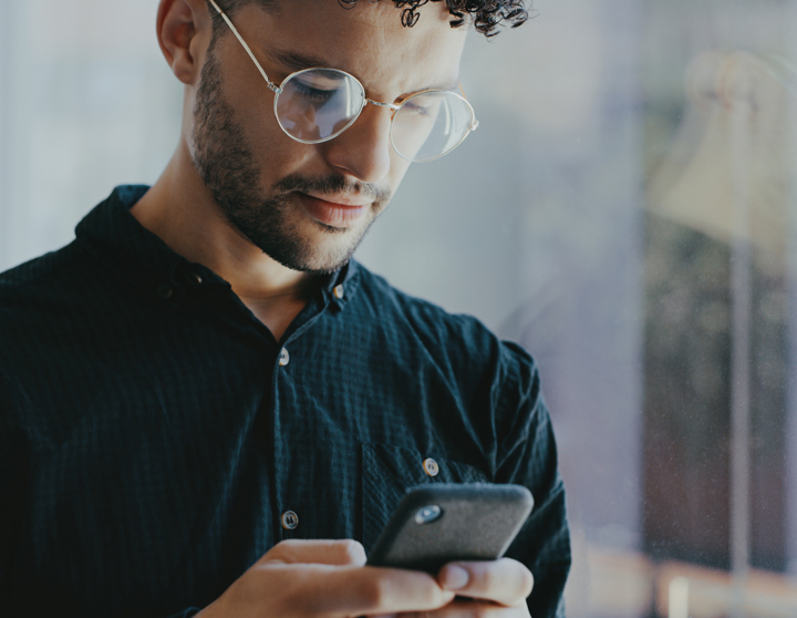 Junger Mann, der sein Smartphone in der Hand hält