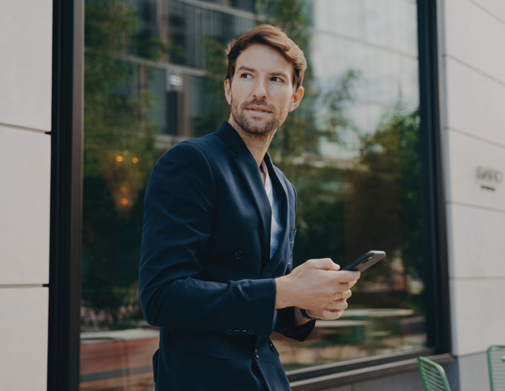 Man leaning towards window looking up from his phone