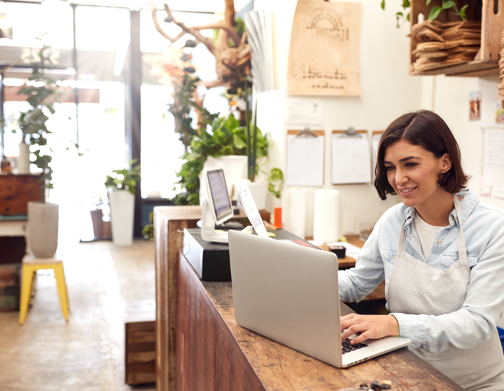 A women is standing next to her laptop smiling