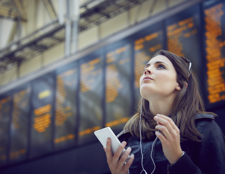 Een jonge vrouw staat bij de vertrekterminal en kijkt naar het bord