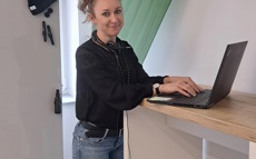 Antonina standing in front of her laptop in a meeting room. Her hair is tied up in a high ponytail