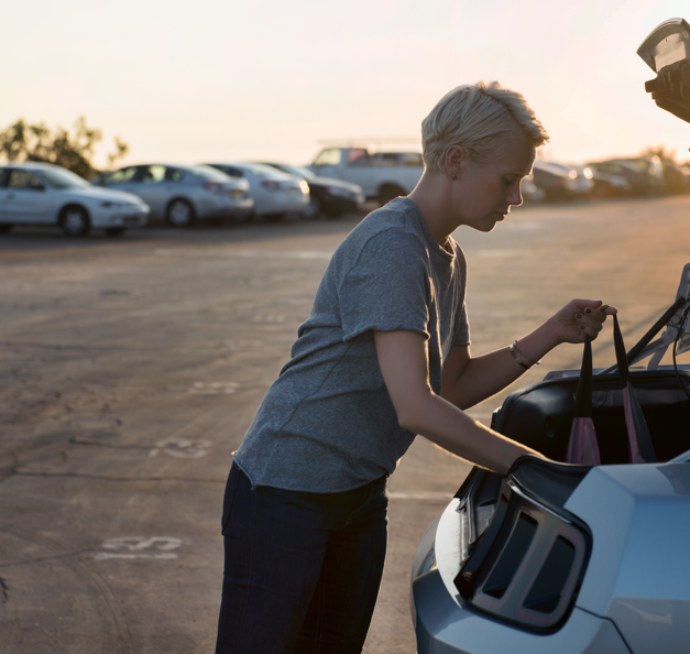A women is standing next to her car in a free flow parking area