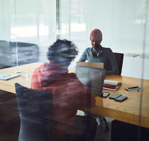 Two persons at desk working on laptops