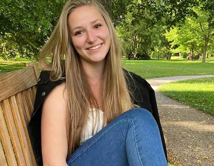 Jule Bohe draußen in einem Park auf einer Bank sitzend