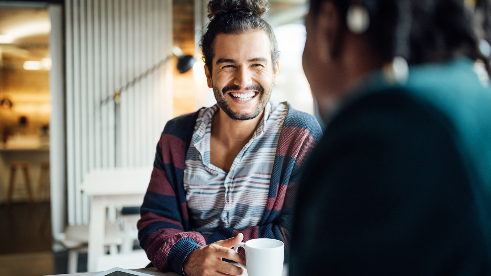 man with a cup of coffee smiling into the camera