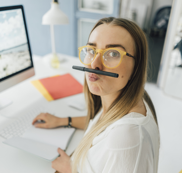student in front of her laptop balancing a pencil on her lips