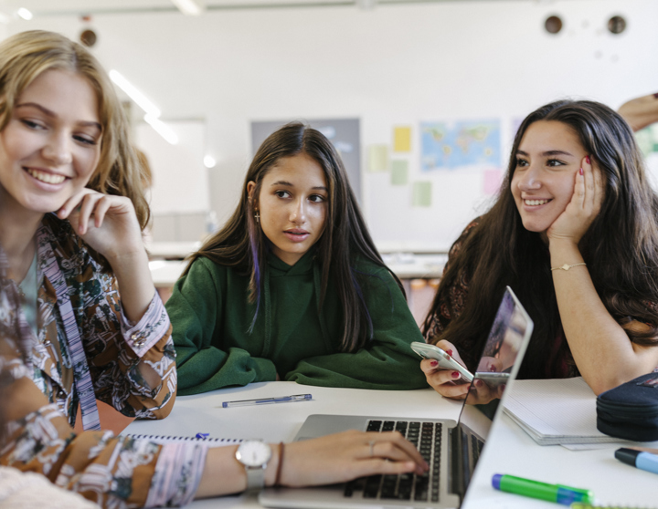 eine Gruppe von Schülerinnen, die vor ihren Schulbüchern sitzt