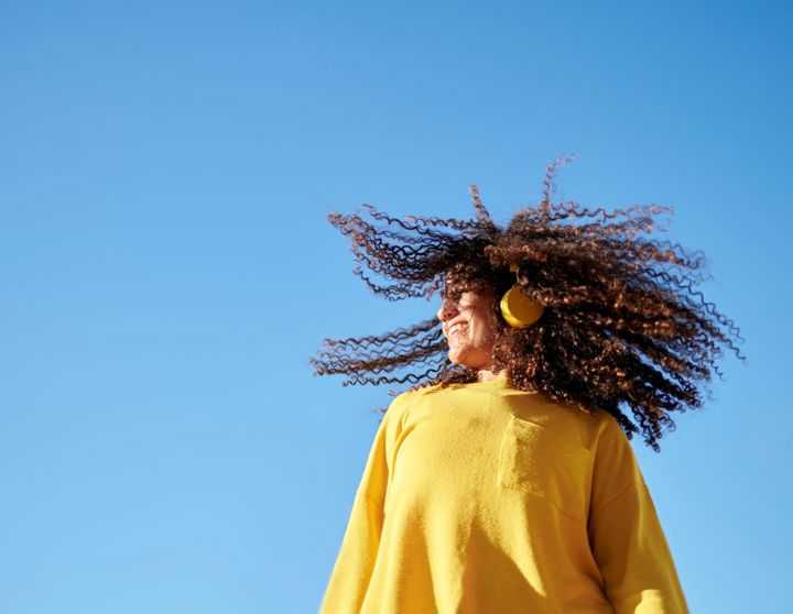 Een gelukkige jonge vrouw danst met gele koptelefoon op een mooie winterdag