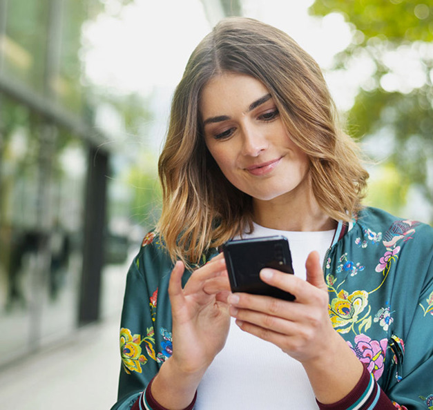 Young, smiling woman with her smartphone in her hands.